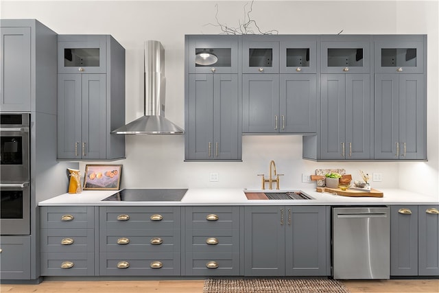 kitchen featuring sink, wall chimney exhaust hood, gray cabinets, black electric stovetop, and light hardwood / wood-style floors