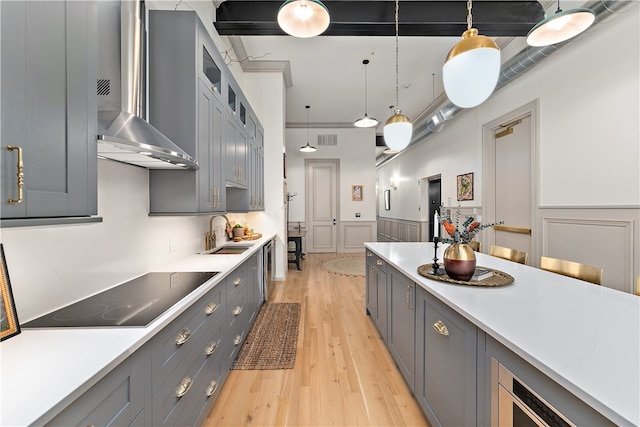 kitchen featuring hanging light fixtures, gray cabinets, sink, and black electric stovetop