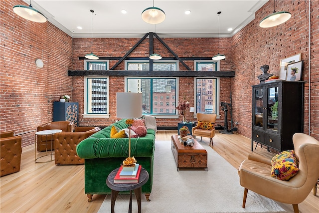 living room with wood-type flooring, ornamental molding, a high ceiling, and brick wall