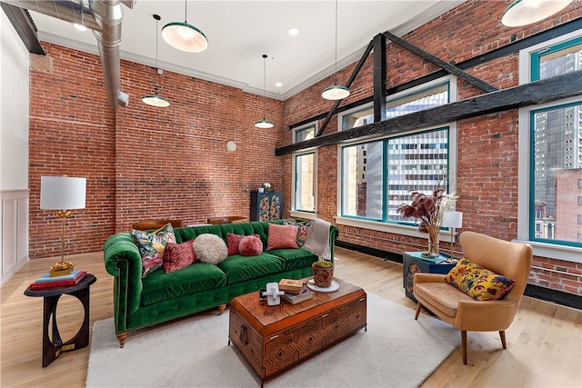 living room with brick wall, light hardwood / wood-style flooring, and a towering ceiling