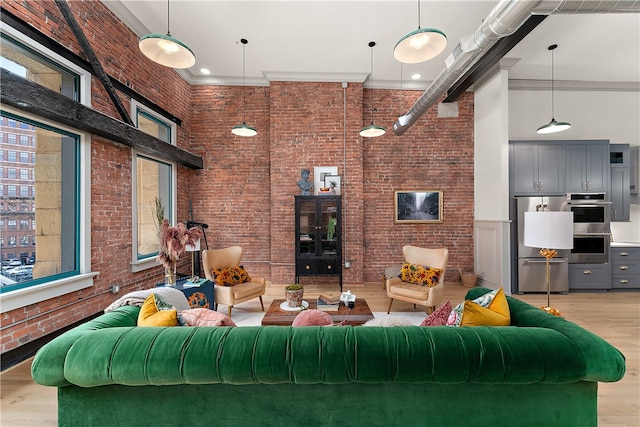 living room featuring brick wall, a towering ceiling, and ornamental molding