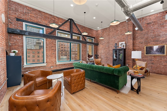 living room featuring brick wall, a towering ceiling, and light hardwood / wood-style floors