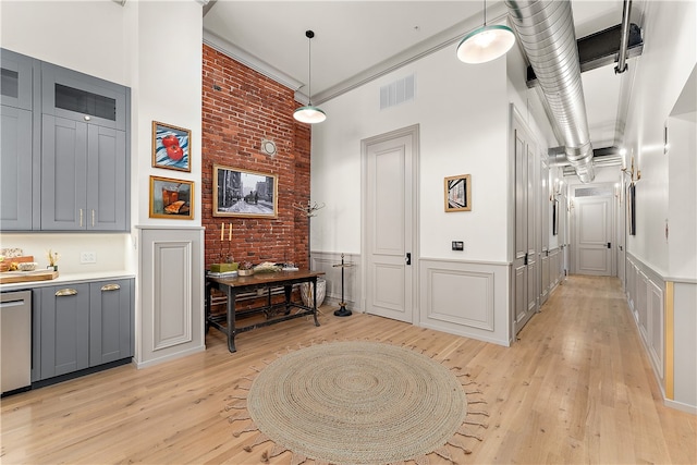 hallway featuring brick wall, light hardwood / wood-style flooring, and a high ceiling