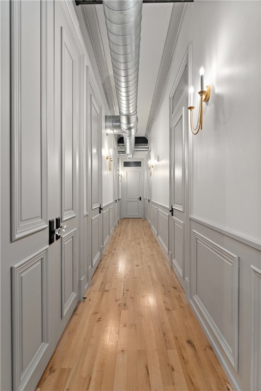 corridor with ornamental molding and light hardwood / wood-style floors