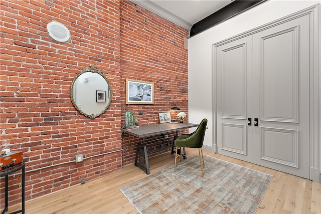 office area with light hardwood / wood-style floors and brick wall