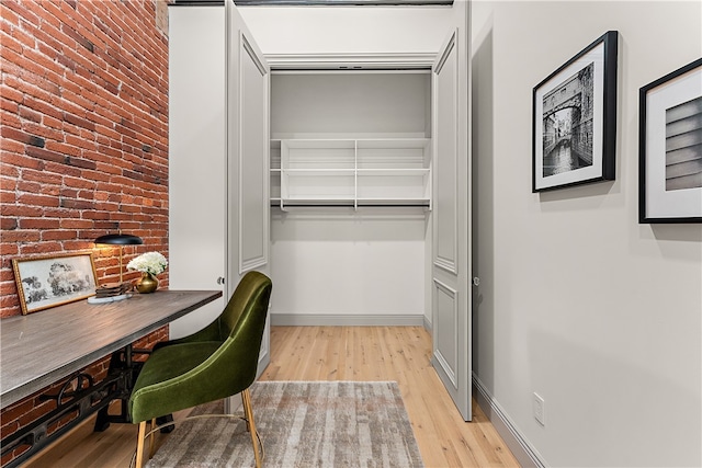 home office featuring brick wall and light hardwood / wood-style floors