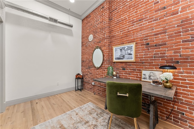 office with brick wall and light hardwood / wood-style floors