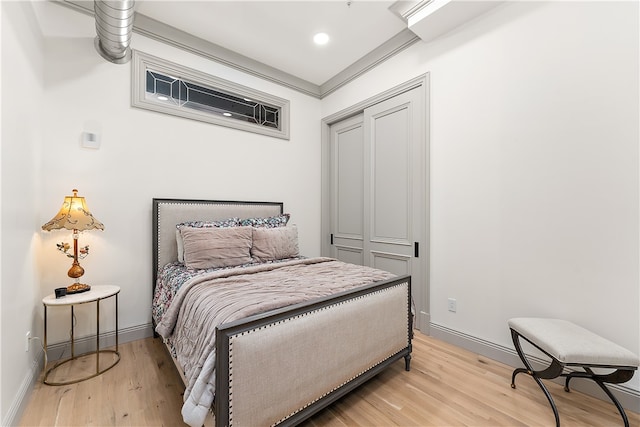 bedroom featuring a closet, crown molding, and light wood-type flooring