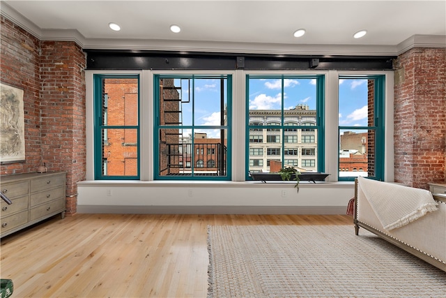 unfurnished bedroom with light hardwood / wood-style floors, multiple windows, and brick wall