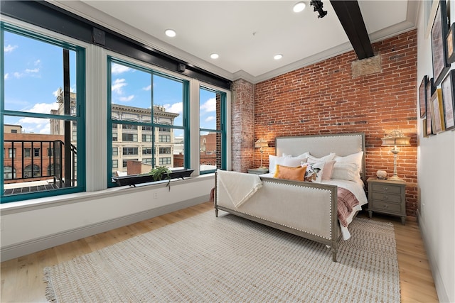 bedroom featuring brick wall, beamed ceiling, and light wood-type flooring