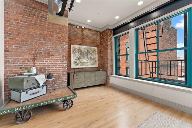 interior space featuring light wood-type flooring, crown molding, and brick wall