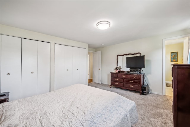 bedroom featuring multiple closets and light carpet