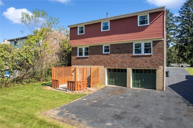 back of property featuring a garage and a lawn