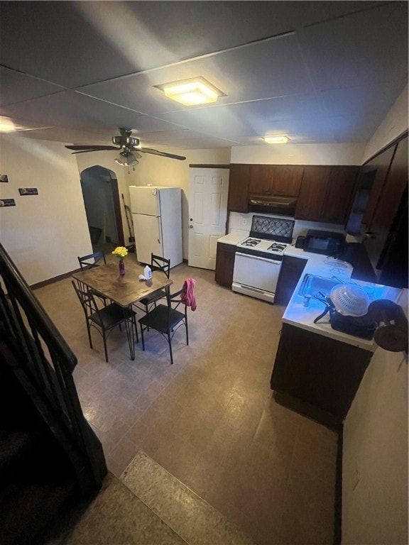 kitchen featuring white appliances, dark brown cabinetry, and ceiling fan