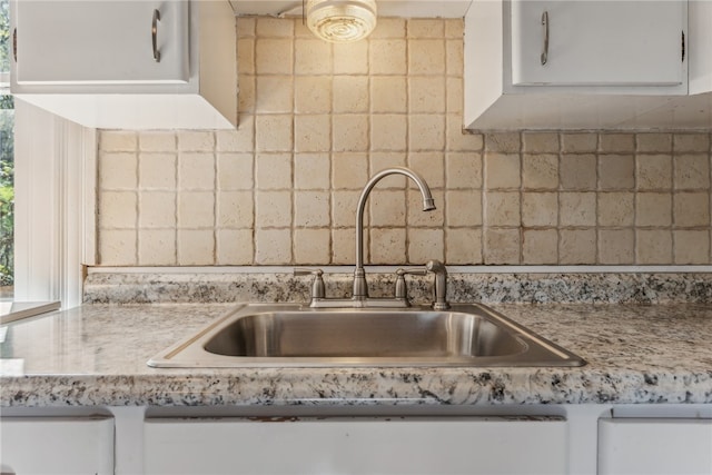 kitchen with light stone counters, sink, decorative backsplash, and white cabinetry