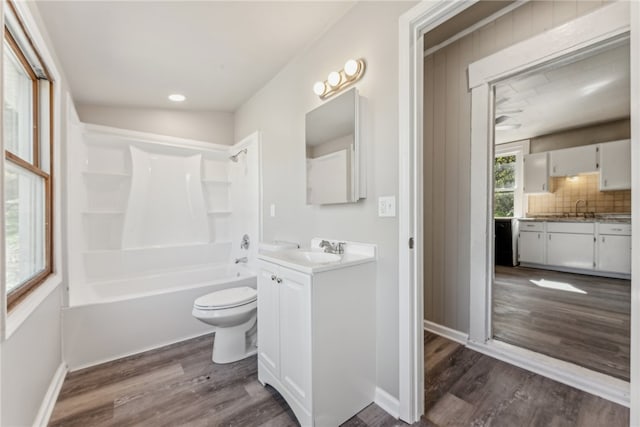 full bathroom with toilet, hardwood / wood-style floors, vanity, backsplash, and  shower combination