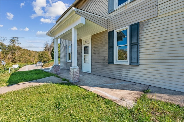 view of exterior entry with a yard and covered porch