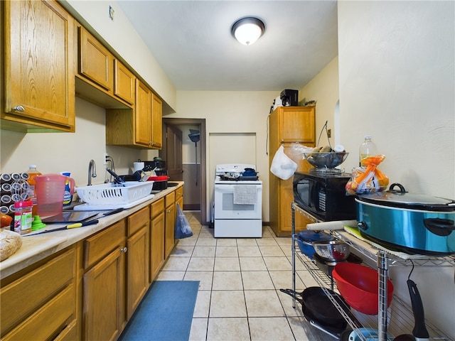 kitchen with light tile patterned flooring, white range with electric stovetop, and sink