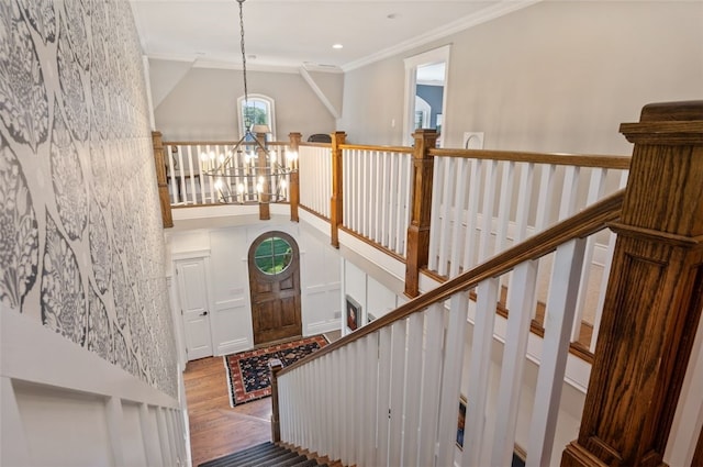 staircase with ornamental molding, a chandelier, and wood-type flooring