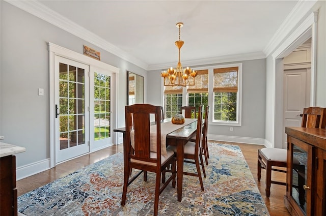 dining area with light hardwood / wood-style floors, ornamental molding, and a chandelier