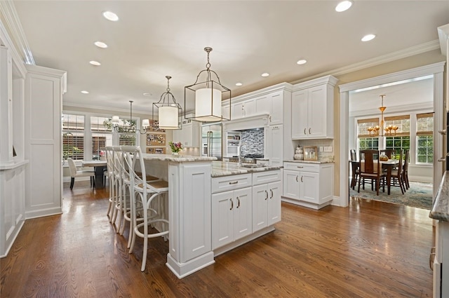 kitchen featuring a healthy amount of sunlight, an island with sink, and white cabinets