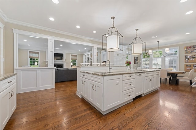 kitchen with white cabinetry, a kitchen island with sink, pendant lighting, and a wealth of natural light