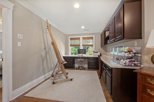 kitchen featuring built in desk, dark brown cabinets, ornamental molding, and hardwood / wood-style floors