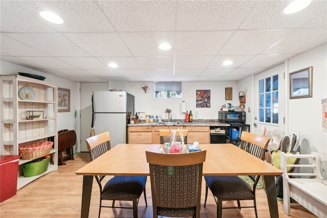 dining space with light hardwood / wood-style flooring and a paneled ceiling