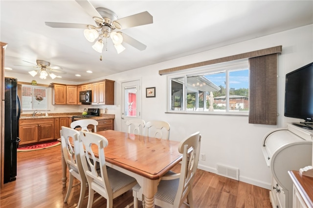 dining room with ceiling fan, sink, and light hardwood / wood-style floors