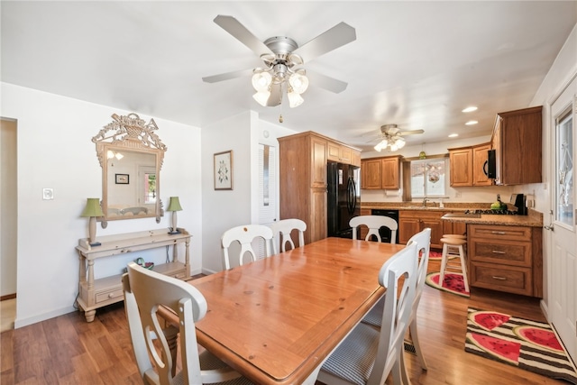 dining space with ceiling fan, sink, and dark wood-type flooring