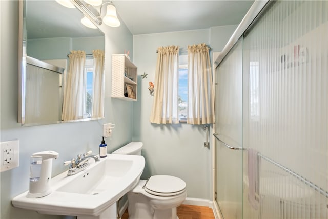 bathroom with an enclosed shower, a healthy amount of sunlight, hardwood / wood-style floors, and toilet