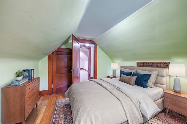 bedroom with light wood-type flooring and vaulted ceiling