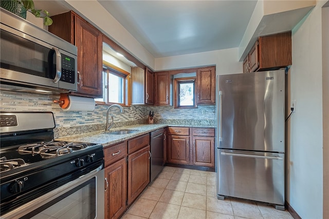 kitchen featuring light tile patterned floors, sink, tasteful backsplash, stainless steel appliances, and light stone countertops