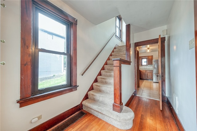 stairs with hardwood / wood-style floors and a wealth of natural light