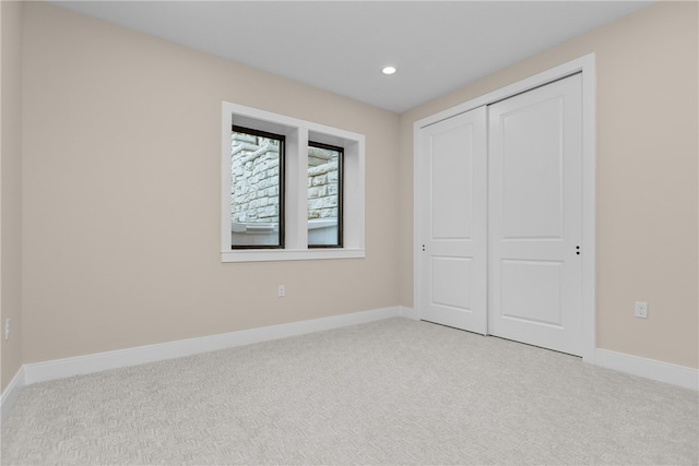 unfurnished bedroom with light carpet and a closet