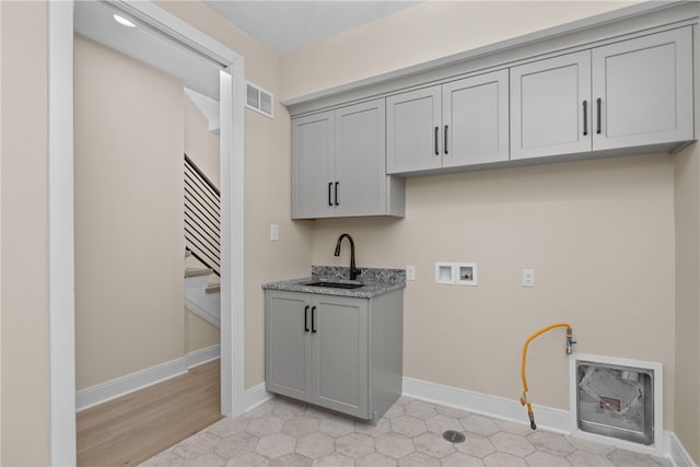 clothes washing area featuring washer hookup, sink, light hardwood / wood-style floors, and cabinets