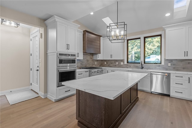 kitchen with white cabinets, appliances with stainless steel finishes, and lofted ceiling with skylight