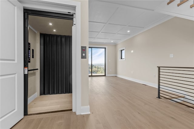 hall with light hardwood / wood-style floors, crown molding, and elevator