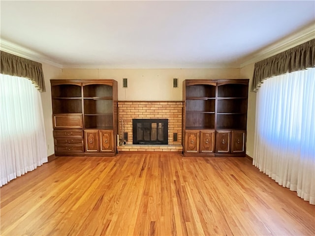 unfurnished living room featuring a brick fireplace, a healthy amount of sunlight, and light hardwood / wood-style flooring