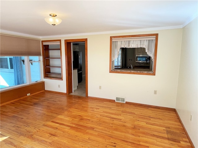 empty room featuring light wood-type flooring and ornamental molding