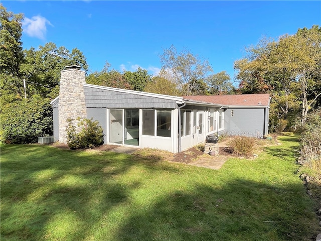 back of property featuring a sunroom and a lawn