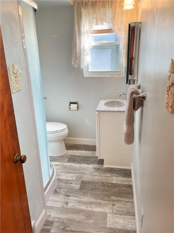 bathroom with wood-type flooring, vanity, a shower with shower door, and toilet