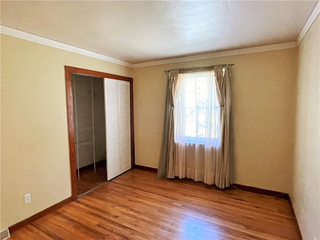 unfurnished bedroom with a closet, crown molding, and hardwood / wood-style flooring