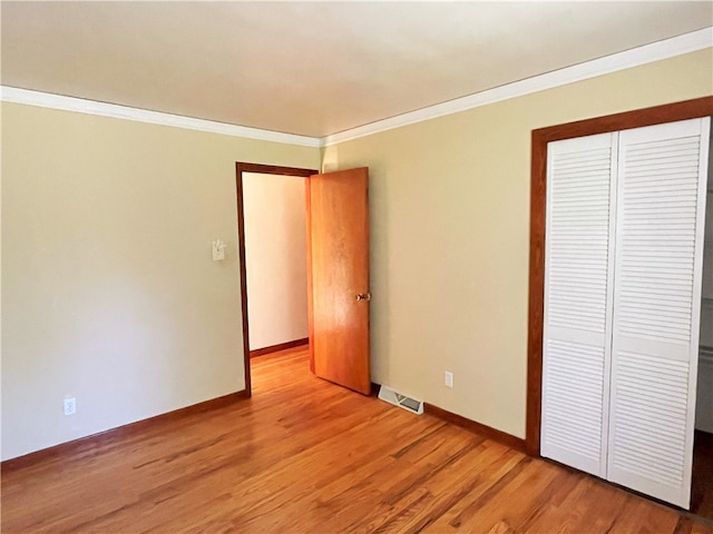 unfurnished bedroom featuring a closet, crown molding, and hardwood / wood-style flooring