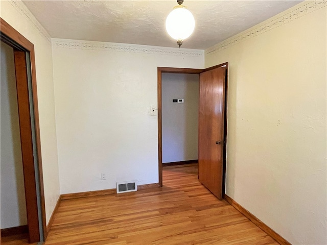 spare room featuring light hardwood / wood-style floors, crown molding, and a textured ceiling