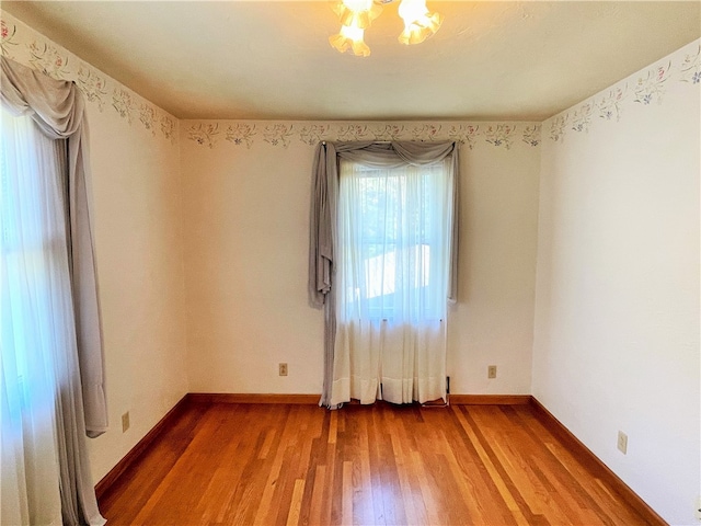 unfurnished room with hardwood / wood-style floors and a chandelier