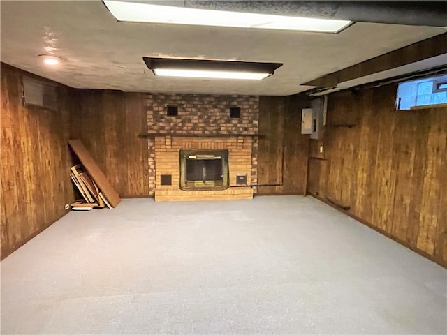 basement featuring a brick fireplace, carpet, and wooden walls