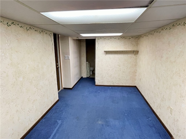 basement with a drop ceiling and dark carpet