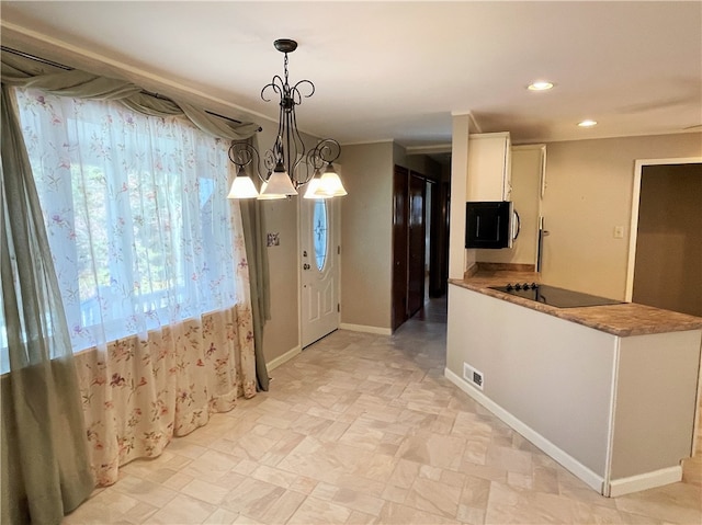 kitchen featuring pendant lighting, white cabinetry, a chandelier, and black electric stovetop