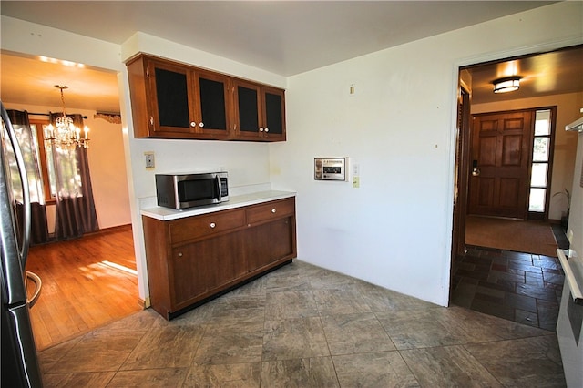 kitchen with pendant lighting, stainless steel appliances, an inviting chandelier, and dark hardwood / wood-style flooring